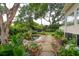 Landscaped backyard featuring a pond, stone pathway, and beautiful plants and trees at 1511 Fairway Dr, Charleston, SC 29412