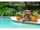 Close-up of pool waterfall feature surrounded by vibrant flowers and plants at 1511 Fairway Dr, Charleston, SC 29412