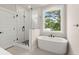 Bright bathroom featuring a soaking tub next to a large window and a glass enclosed shower with black hardware at 1577 Periwinkle Dr, Mount Pleasant, SC 29466