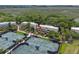 Aerial view features community tennis courts near townhomes with balconies, surrounded by lush greenery with marshland in the distance at 1627 Live Oak Park, Seabrook Island, SC 29455