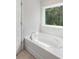 Sunlit white bathtub with a large window offering a view of the lush, green surroundings at 174 Red Bluff St, Summerville, SC 29483