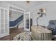 A modern office with a curved desk, stylish decor, hardwood floors, and a view of the staircase through French doors at 183 Calm Water Way, Summerville, SC 29486
