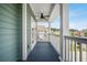 Covered porch featuring wood-look floors, white railings, and exterior green siding at 183 Calm Water Way, Summerville, SC 29486