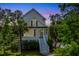 Charming home featuring a welcoming front porch and neatly landscaped yard with mature trees and colorful red window shutters at 2301 N Creek Dr, Mount Pleasant, SC 29466