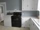 Functional kitchen with black oven and washer dryer next to a white sink at 301 Ridge St, Saint George, SC 29477