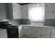 Functional kitchen with white cabinets, counters, black oven and a window above the sink at 301 Ridge St, Saint George, SC 29477