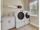 Bright laundry room featuring white washer and dryer, storage cabinets, sink, and a window for natural light at 3041 Robeson Trce, Johns Island, SC 29455