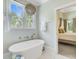 Bright bathroom featuring a freestanding tub, chandelier, and an open doorway to a cozy bedroom at 62 Eastlake Rd, Mount Pleasant, SC 29464