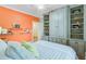 Stylish bedroom boasts custom built-in shelving and an orange accent wall at 62 Eastlake Rd, Mount Pleasant, SC 29464