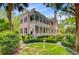 Charming two-story pink home featuring double balconies, a manicured lawn and a lush garden at 62 Eastlake Rd, Mount Pleasant, SC 29464