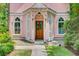 Charming front entrance with arched windows, a wooden door, and lush greenery at 62 Eastlake Rd, Mount Pleasant, SC 29464