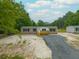 Aerial view of a tan manufactured home with a wood porch, gray driveway, and green trees at 106 Swanson Dr, Summerville, SC 29483