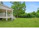 View of the side of the home with a white porch leading to a lush yard with vibrant green grass and vegetation at 1076 Williams Rd, Charleston, SC 29412
