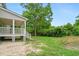 View of the side of the home with a white porch leading to a spacious yard with trees and vegetation at 1076 Williams Rd, Charleston, SC 29412