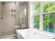Modern bathroom features a glass-enclosed shower, soaking tub, and a window with a view of greenery at 1076 Williams Rd, Charleston, SC 29412