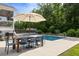 Backyard pool area with a dining table set and umbrella, surrounded by lush greenery and landscaping at 1825 Crossbill Trl, Hanahan, SC 29410