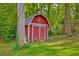 Charming red storage shed with decorative detail, nestled among trees in the backyard at 202 Hunt Club Dr, Summerville, SC 29485