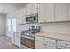 Close up of kitchen with stainless steel stove and oven, microwave, white cabinets, and quartz countertops at 206 Camellia Bloom Dr, Moncks Corner, SC 29461