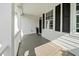 Inviting covered front porch with gray stained wood flooring and white railing, and black shutters at 2152 Pentland Dr, Charleston, SC 29412