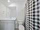 Neutral-toned bathroom with a white vanity, toilet, and a black and white checkered shower curtain at 223 Granton Edge Ln, Summerville, SC 29486