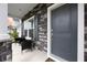 Close-up of a front porch with stone pillars, a dark-gray door, and a cozy seating area at 223 Granton Edge Ln, Summerville, SC 29486