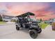 The black golf cart sits on a concrete driveway of a home in a suburban neighborhood under a colorful sky at 223 Granton Edge Ln, Summerville, SC 29486