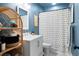 Stylish bathroom with blue walls, a white vanity, striped shower curtain and decorative shelving at 2924 Alabama Dr, North Charleston, SC 29405