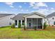 A rear exterior view of a home with a screened in porch and grassy lawn at 3806 Grateful Rd, North Charleston, SC 29420