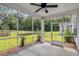 A screened porch with a ceiling fan overlooking a lush green lawn and small pond at 3806 Grateful Rd, North Charleston, SC 29420