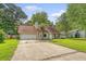 View of the house with a spacious driveway, well-kept lawn, and mature trees at 4606 Moss Ct, North Charleston, SC 29420