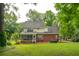 Spacious backyard with lush green grass, mature trees, and a view of the two-story brick home with a screened porch at 5195 Forest Oaks Dr, Hollywood, SC 29449