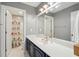 Well-lit bathroom featuring a large mirror, blue cabinets, and an adjacent room with a shower-tub combo and a colorful shower curtain at 5195 Forest Oaks Dr, Hollywood, SC 29449