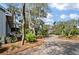 Long driveway with lush landscaping, mature trees, and a glimpse of a cozy blue home at 622 E Cooper Ave, Folly Beach, SC 29439