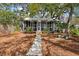 Charming front exterior with a cozy, screened-in porch and a stone path surrounded by greenery at 622 E Cooper Ave, Folly Beach, SC 29439