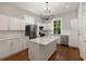 Bright kitchen with white cabinets, quartz countertops, stainless appliances, a center island, and hardwood floors at 8 Pitt St # A, Charleston, SC 29401