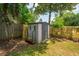 Backyard shed with firewood and fencing, surrounded by lush greenery and mature trees at 8507 William Moultrie Dr, North Charleston, SC 29420