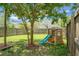 Large grassy backyard with a playground, surrounded by a wooden fence at 8921 Skipping Rock Ln, Summerville, SC 29485