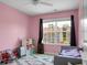 Bright bedroom with pink walls, large window, ceiling fan, and area rug at 8921 Skipping Rock Ln, Summerville, SC 29485