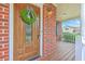 Close-up of the front door with a decorative wreath, brick exterior, and a glimpse of the inviting front porch at 100 Cicero Ct, Goose Creek, SC 29445
