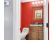 Powder room with red walls, wooden vanity, granite countertop, and stylish mirror, illuminated by sconce lighting at 100 Conset Bay Ct, Goose Creek, SC 29445