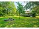 Backyard featuring a grassy lawn, mature trees, and a stone picnic table at 100 S Gum St, Summerville, SC 29483