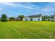 Spacious backyard featuring a well-maintained lawn and white siding home under a beautiful blue sky with clouds at 129 Dovetail Cir, Summerville, SC 29483