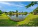 Scenic view of a pond surrounded by lush green grass and community homes under a bright blue sky at 129 Dovetail Cir, Summerville, SC 29483