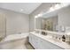 Elegant bathroom featuring a soaking tub with tile surround, a dual sink vanity, and a tiled glass shower at 160 Palm Cove Way, Mount Pleasant, SC 29466