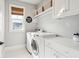 This modern laundry room is equipped with white cabinets, a washer, a dryer, and a window for natural light at 1714 Fort Palmetto Cir, Mount Pleasant, SC 29466
