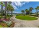 Inviting walkway lined with vibrant flowers and stately palm trees leading to the lake at 1751 Brittlebush Ln, Johns Island, SC 29455