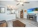 Open living room with hardwood floors, ceiling fan, entertainment center with fireplace, and view into kitchen at 1751 Brittlebush Ln, Johns Island, SC 29455