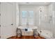 Bright bathroom featuring a soaking tub, glass shower, wood floors, and shuttered windows providing plenty of natural light at 28 Robert Mills Cir, Mount Pleasant, SC 29464