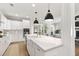 Spacious kitchen featuring a large island with a sink and white marble countertop, white cabinets, and modern appliances at 2828 Wagner Way, Mount Pleasant, SC 29466