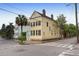 Corner lot featuring a charming yellow two-story home with a palm tree and black shutters at 29 Smith St, Charleston, SC 29401
